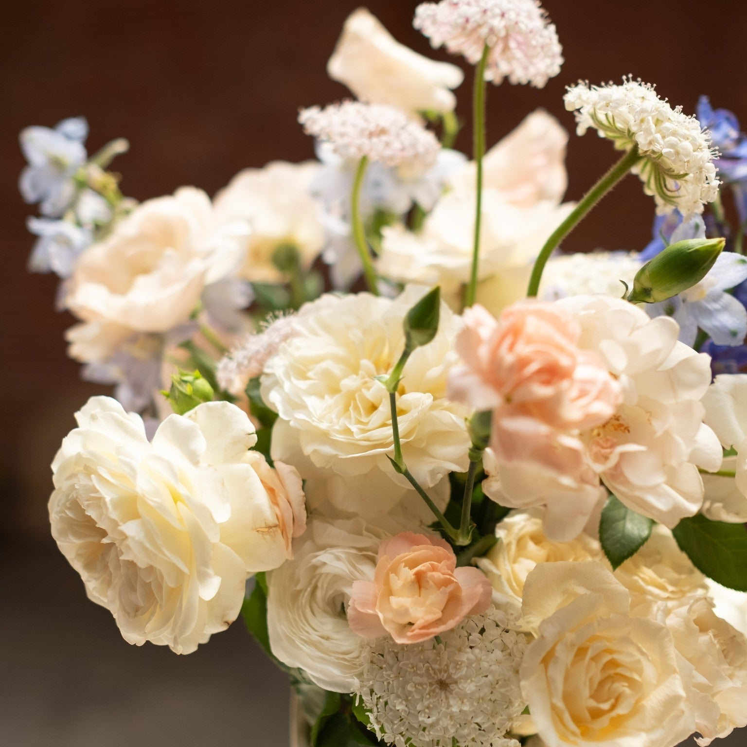 Bouquet of peach, pale yellow and light pink flowers in a vase with a blurred background
